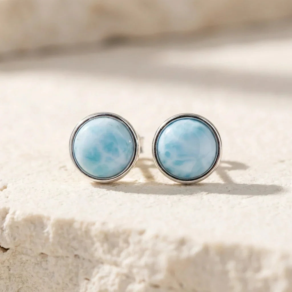 Front view of pale-blue round stud earrings in silver-tone rims.