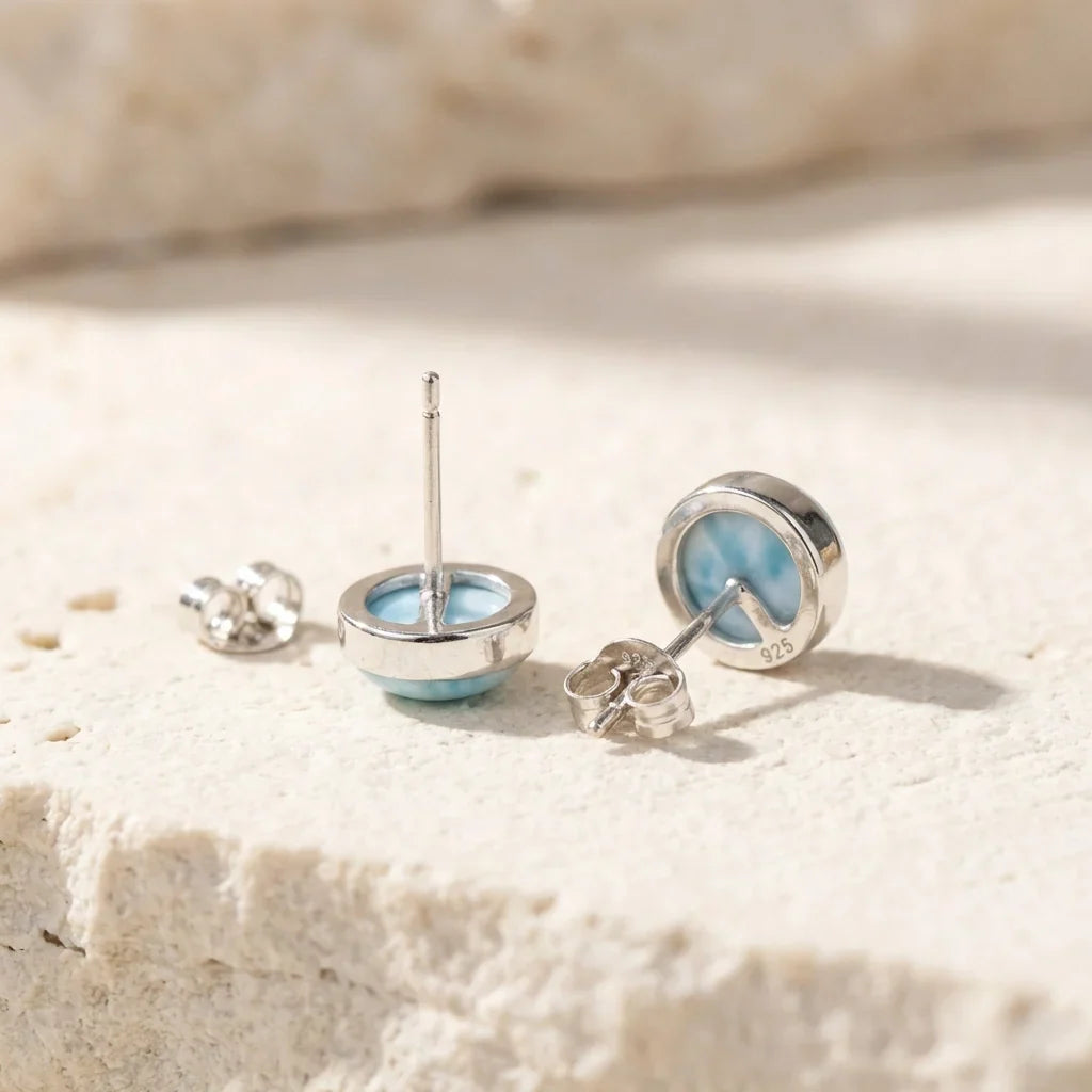 Back view of pale-blue round stud earrings showing posts and butterfly backs.