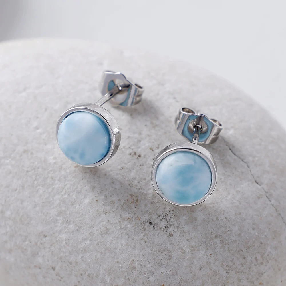Pale-blue round stud earrings in silver-tone settings, with posts and backs visible.