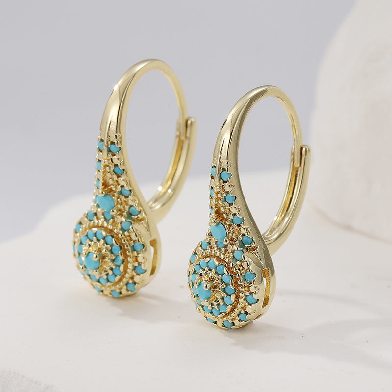 Gold-tone curved teardrop earrings covered with clusters of small turquoise-colored round accents.