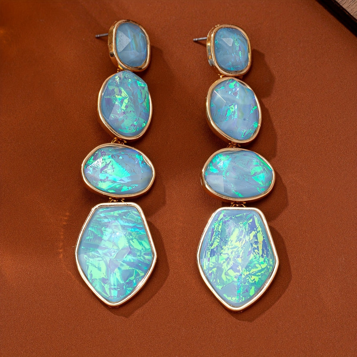 Long earrings with four stacked aqua iridescent-looking sections and warm gold-tone borders.