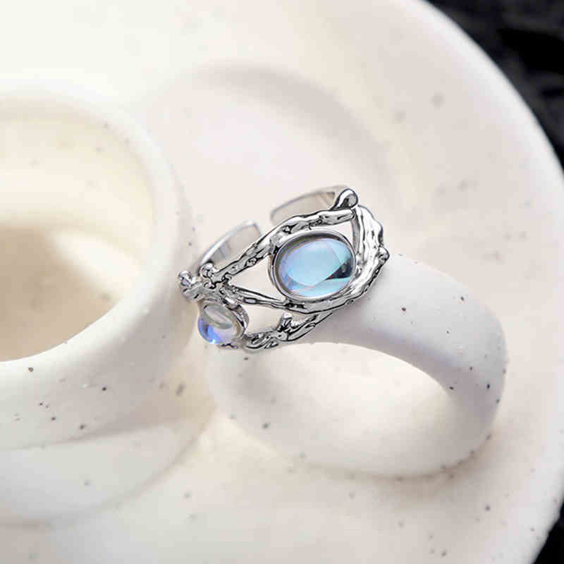 Silver-tone branch ring with an oval pale-blue center and small decorative accents.