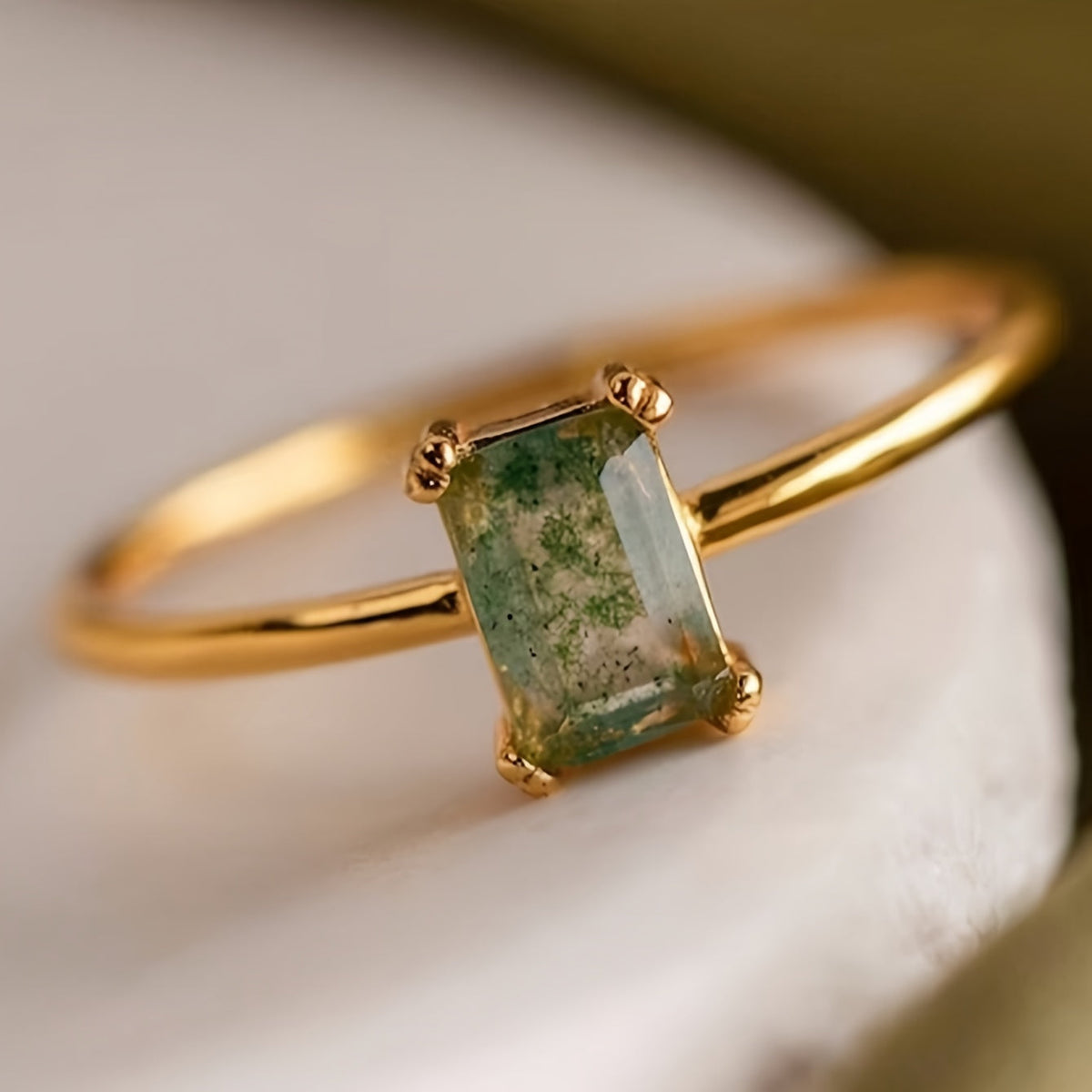 Gold-tone ring with a rectangular green patterned center and four corner prongs.