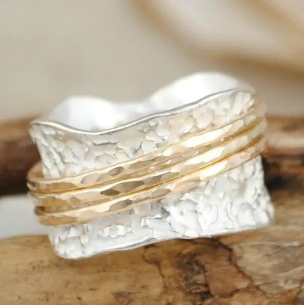 Maeve spinner ring close-up showing the hammered band and three gold-tone rings