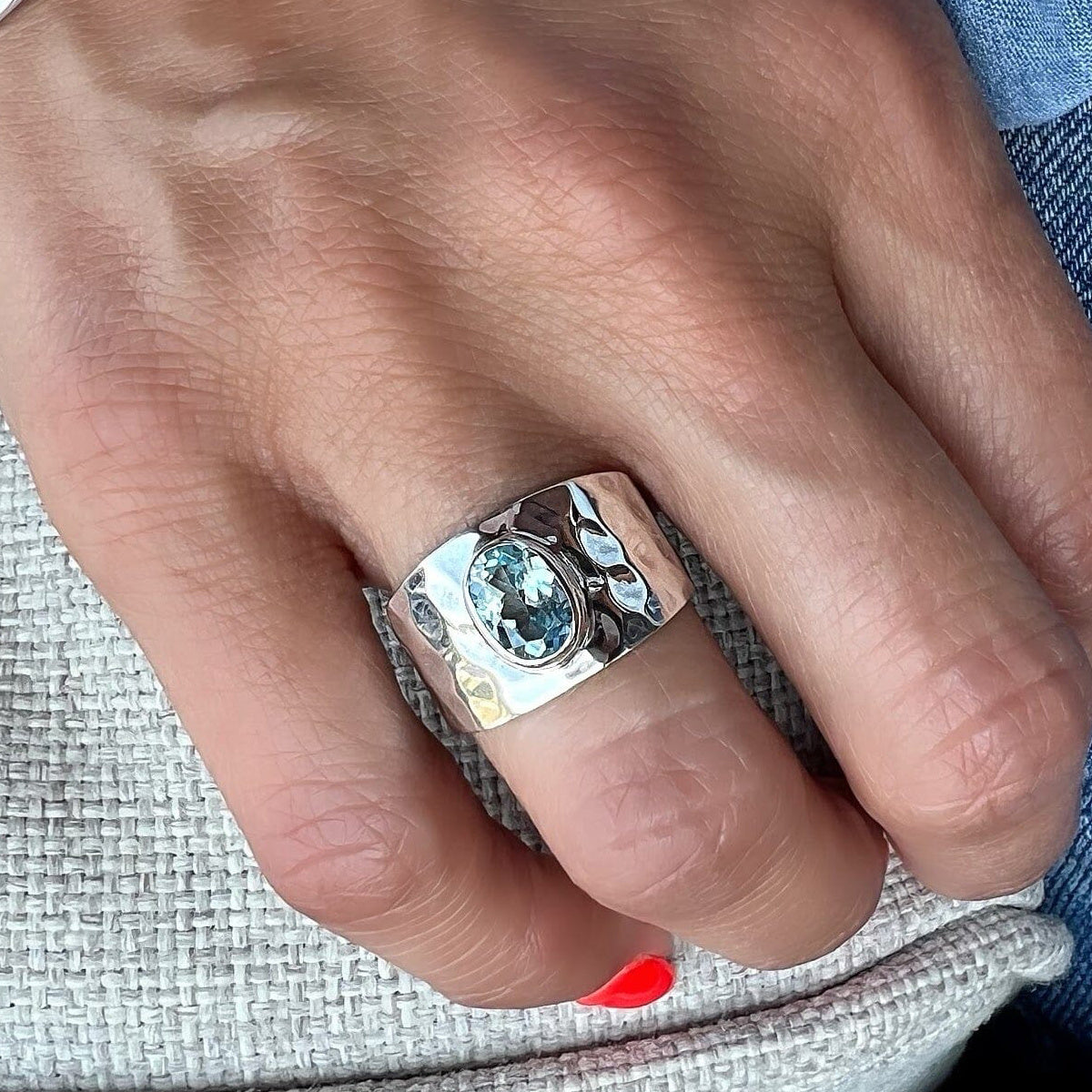 Aqua centerpiece ring on a finger, showing the broad textured silver-tone band.