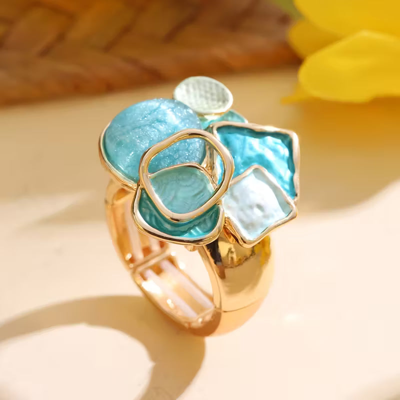 Cluster ring with aqua, turquoise blue, and milky white geometric accents above a broad gold-tone band.