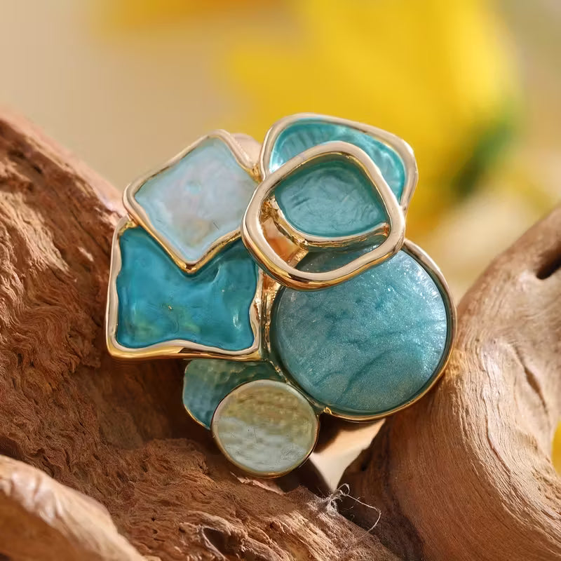 Cluster ring with aqua, turquoise blue, and milky white geometric accents above a broad gold-tone band.