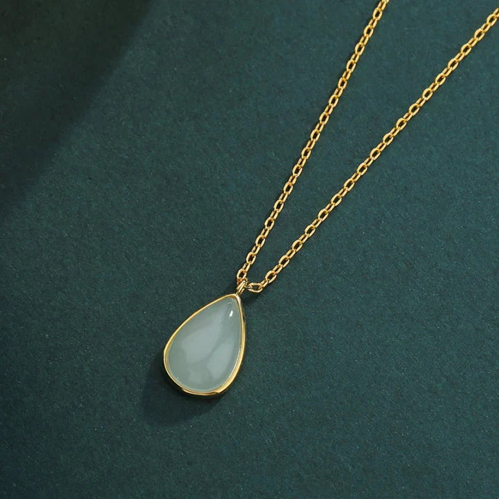Pale-green teardrop pendant in a smooth gold-tone frame on a fine gold-tone chain.