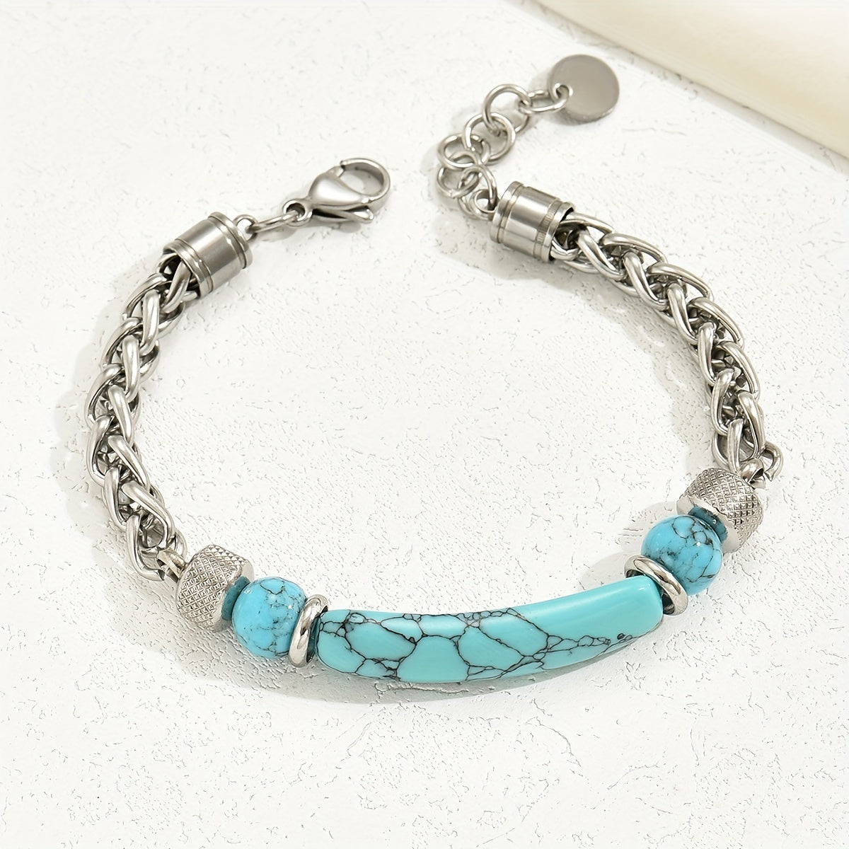 Turquoise-colored curved bar bracelet with round beads, interwoven silver-tone links, a lobster clasp, and an extender.