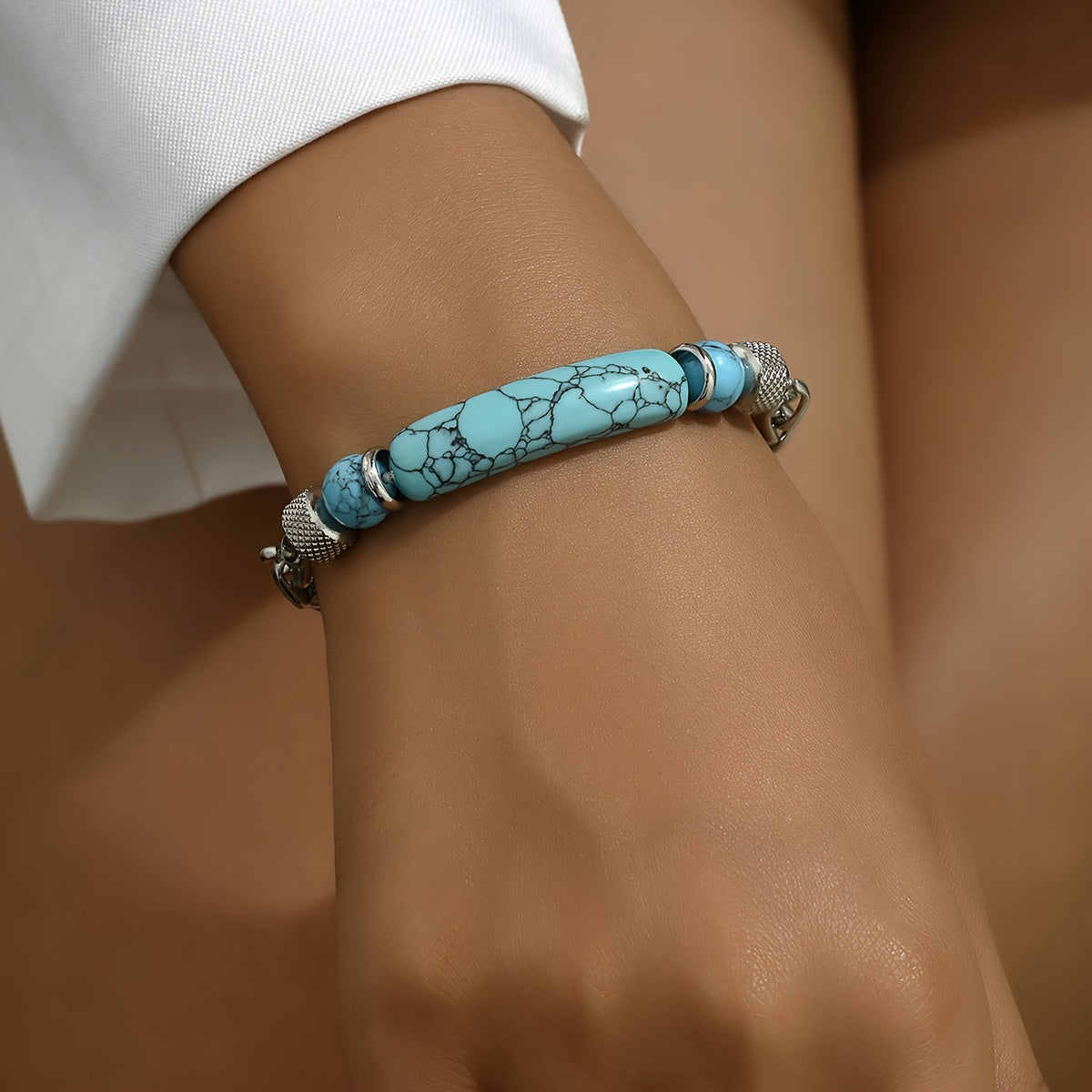 Turquoise-colored curved bar bracelet with silver-tone chain links worn on the wrist.