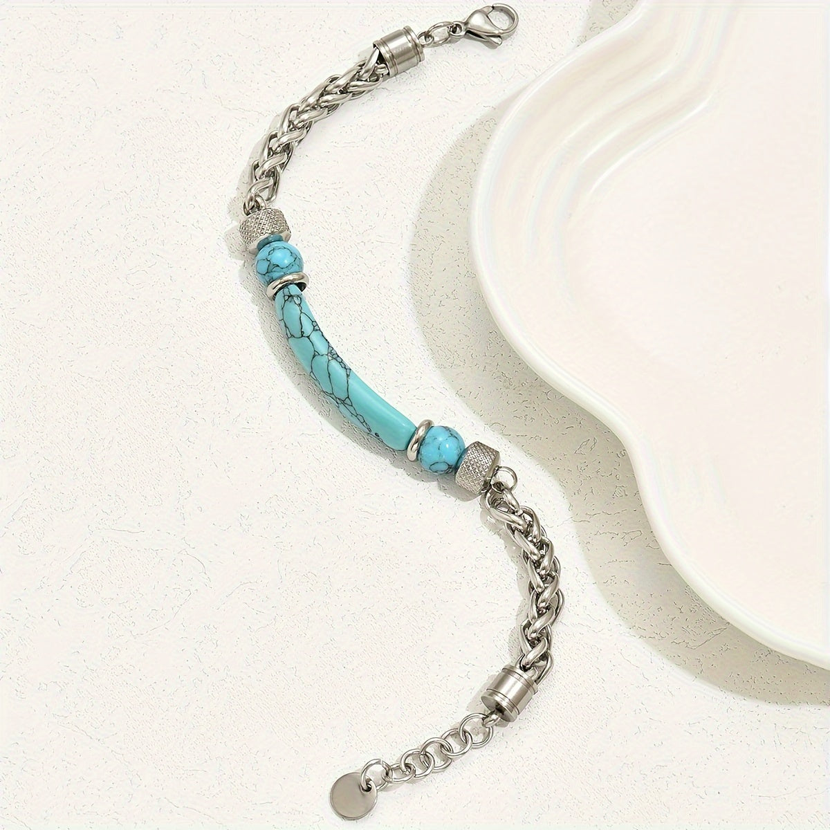 Turquoise-colored curved bar bracelet with round beads, interwoven silver-tone links, a lobster clasp, and an extender.