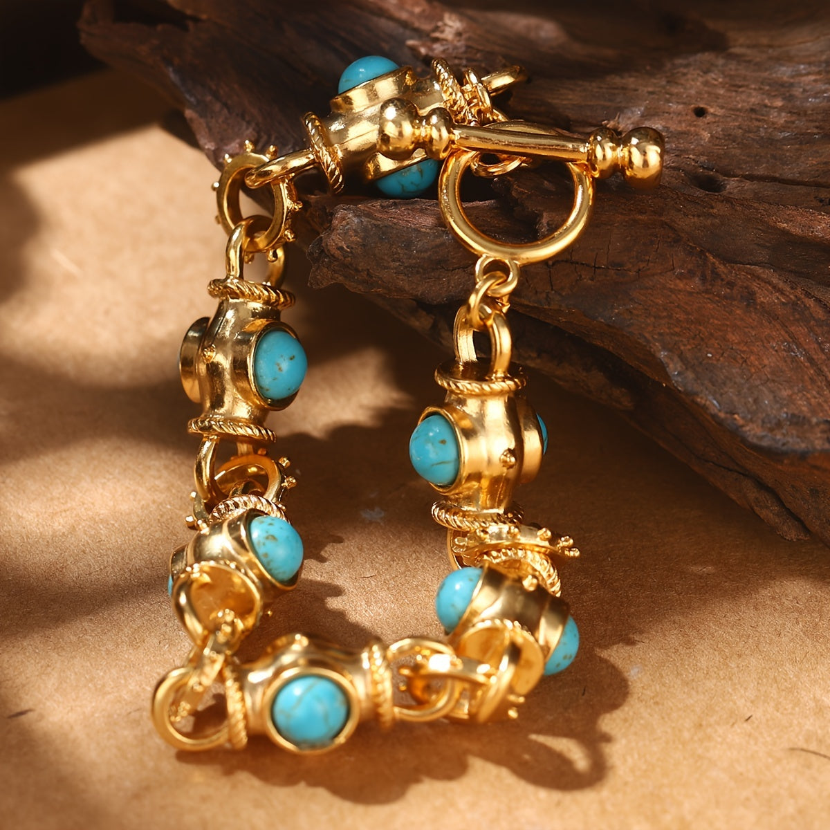 Bracelet with rounded turquoise-colored cabochons, decorative gold-tone links, and a ring-and-bar toggle closure.