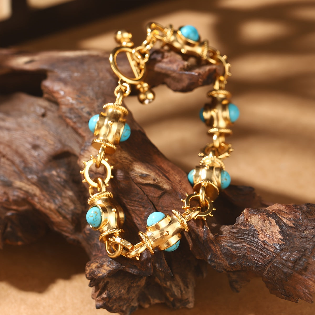 Bracelet with rounded turquoise-colored cabochons, decorative gold-tone links, and a ring-and-bar toggle closure.