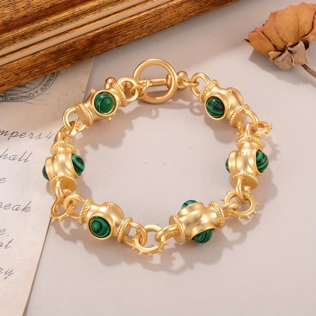 Gold-tone toggle link bracelet with rounded green striped cabochon-style accents.