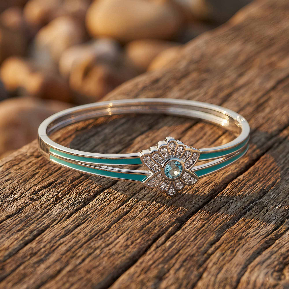 Bangle with an icy blue floral center, clear petal accents, and aqua lines along the open band.