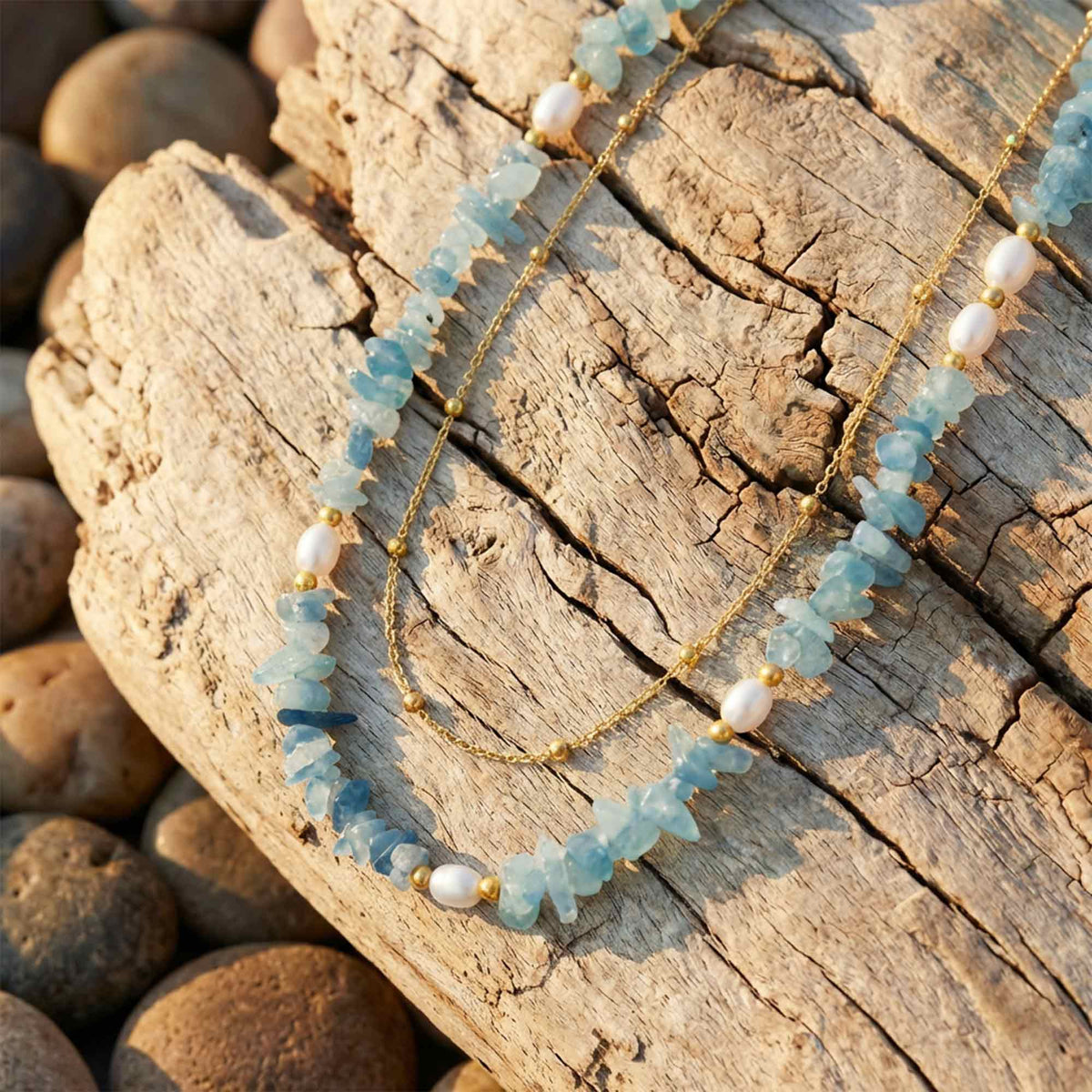 Layered necklace with irregular icy blue beads, spaced round white beads, and a fine gold-tone strand.