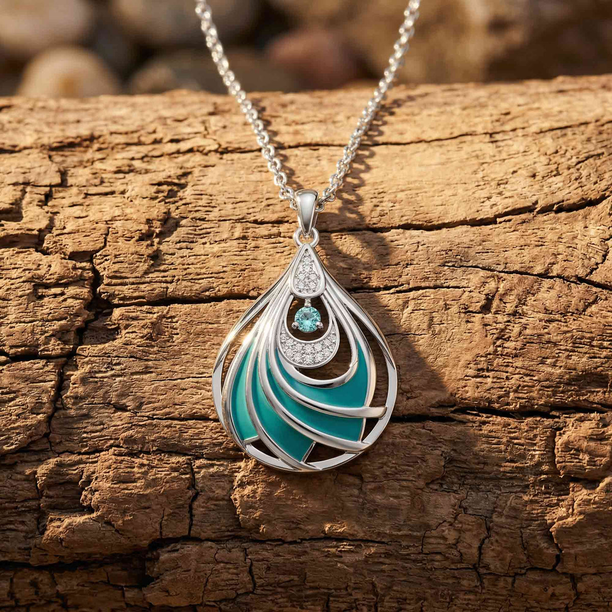 Openwork teardrop pendant with silver-tone curved lines, aqua sections, and a round blue accent near the top.
