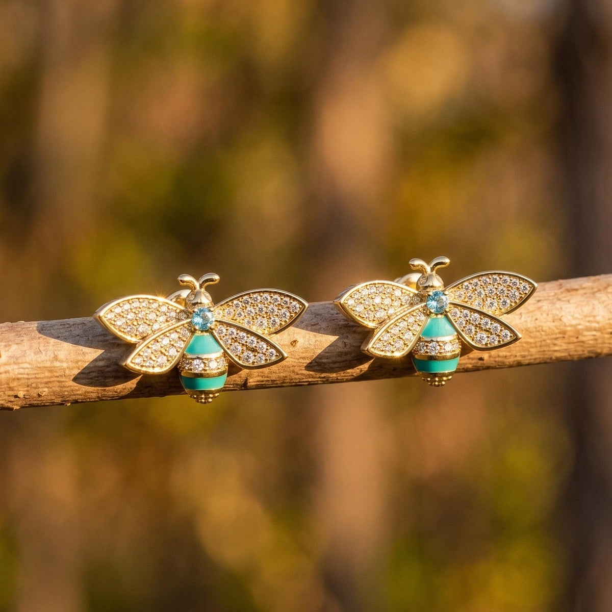 Gold-tone bee stud earrings with clear wing accents, aqua bodies, and small blue centers.