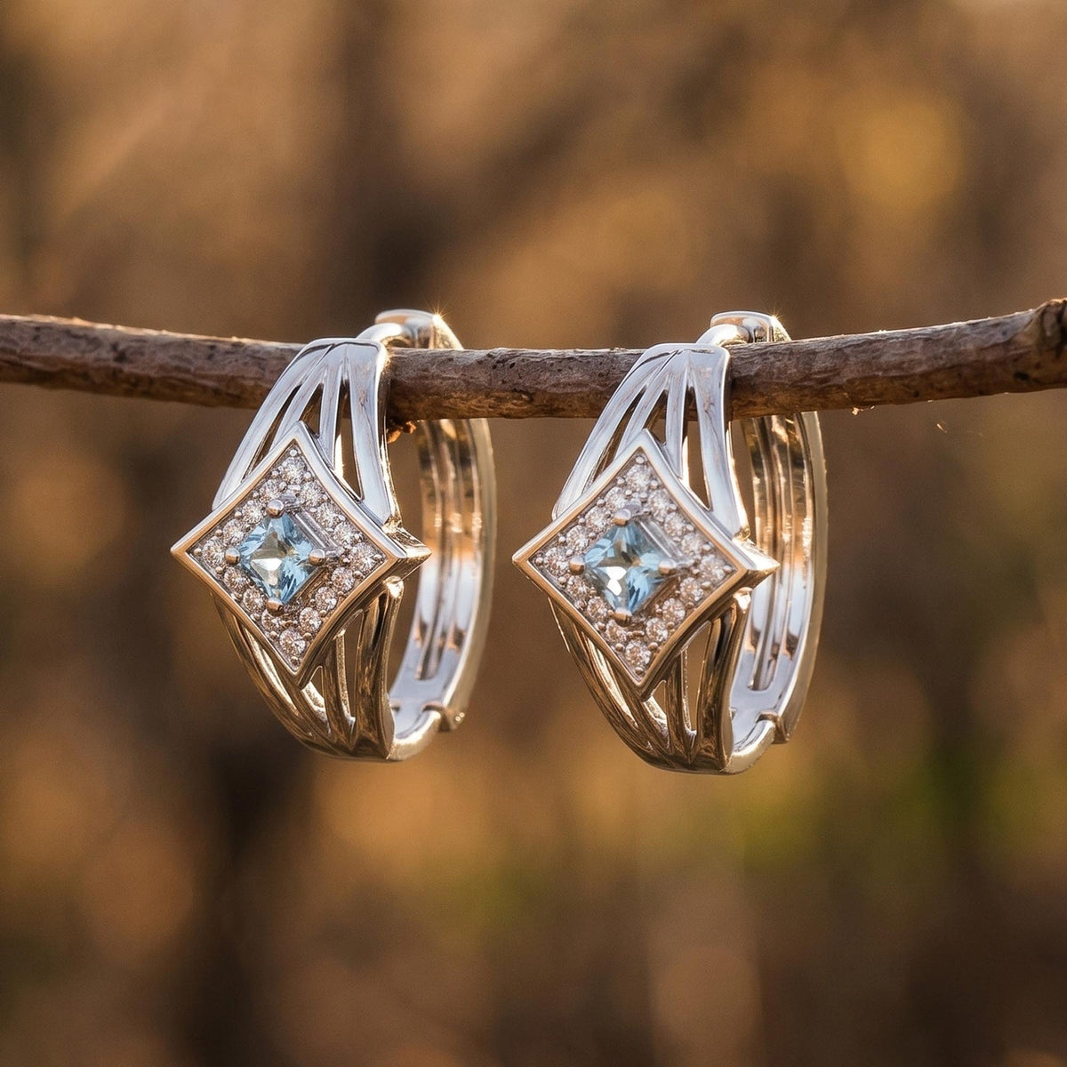 Open silver-tone hoop earrings with icy blue square centers in diamond-shaped clear-accent frames.