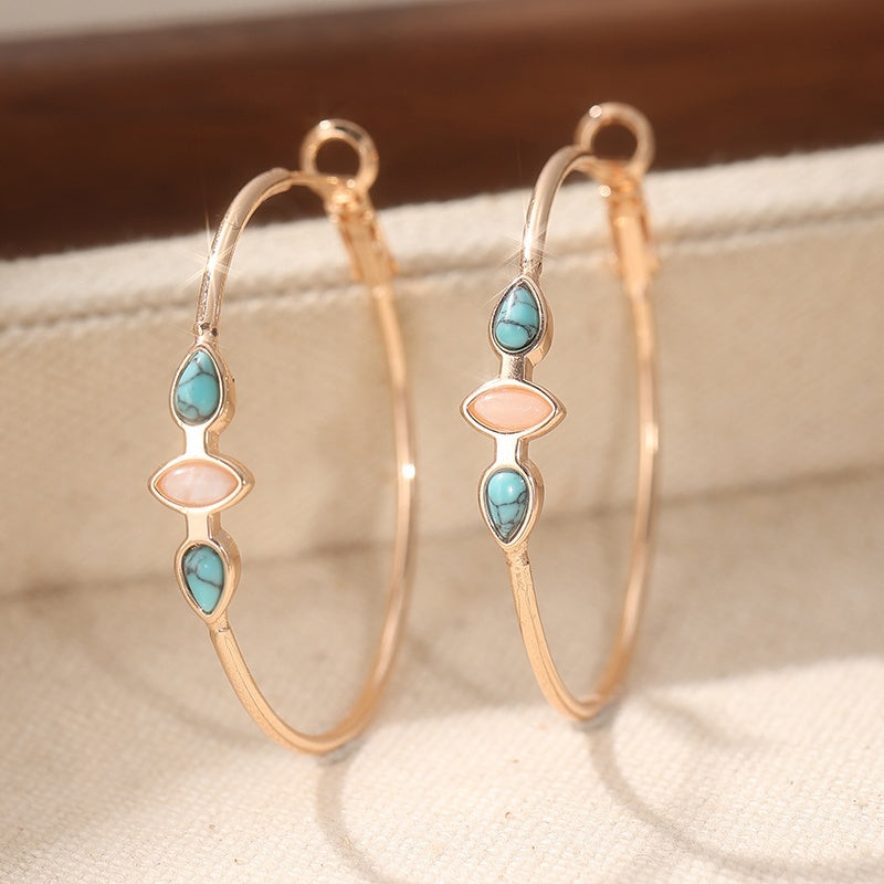 Warm gold-tone hoops with turquoise-colored teardrop accents and a pale-pink center accent.