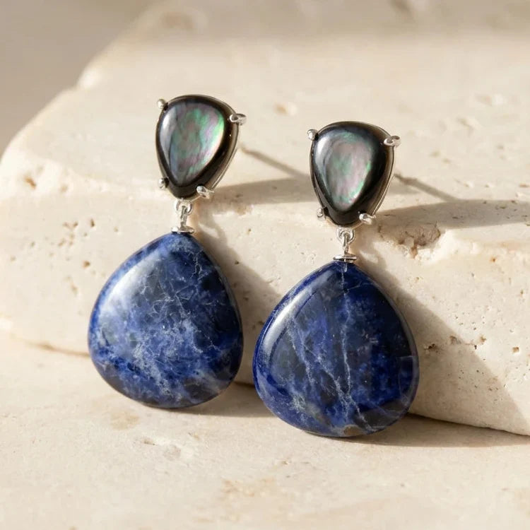 Dark-blue rounded teardrop earrings below smaller pear-shaped iridescent-looking stud tops.