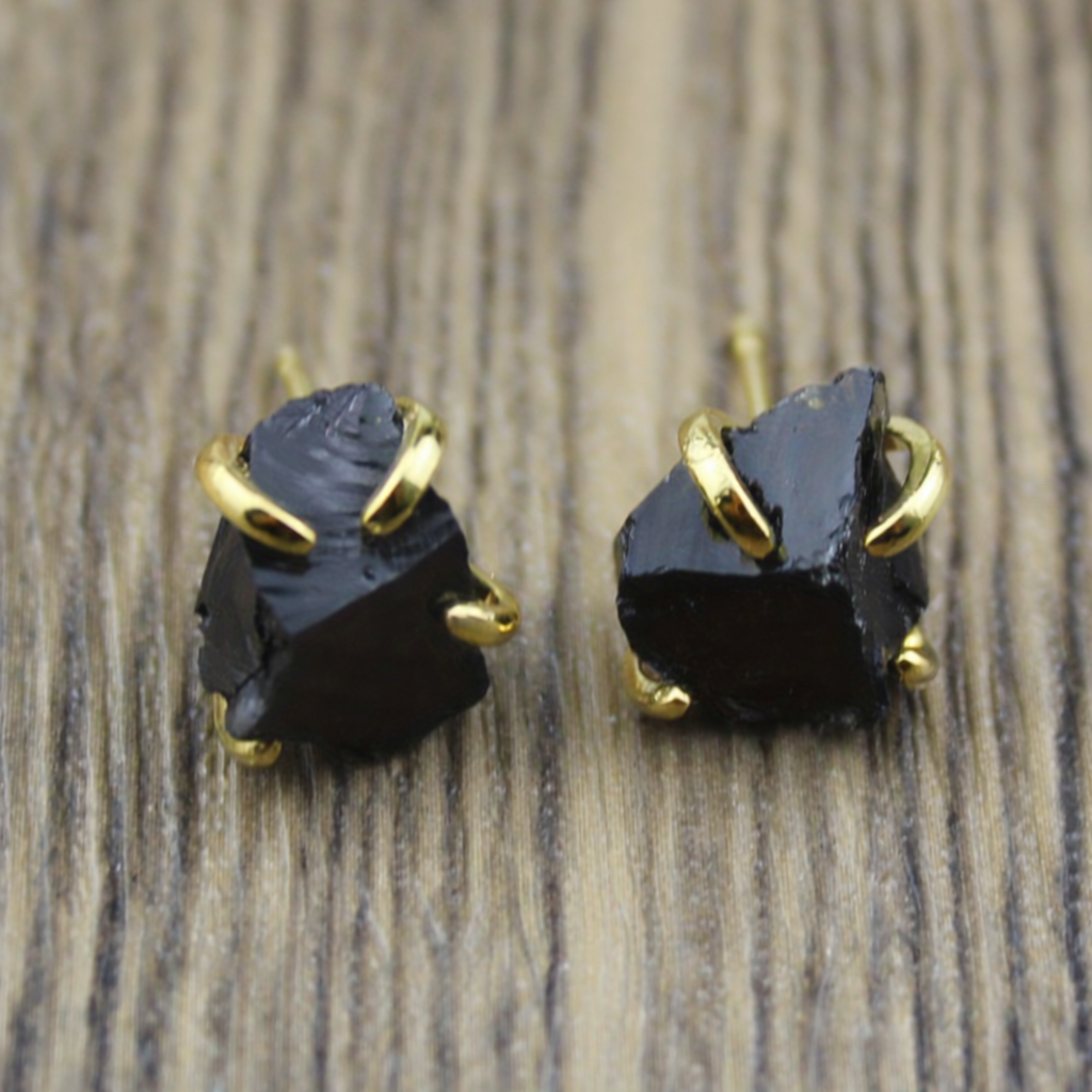 Black irregular textured stud earrings held by gold-tone claw settings.