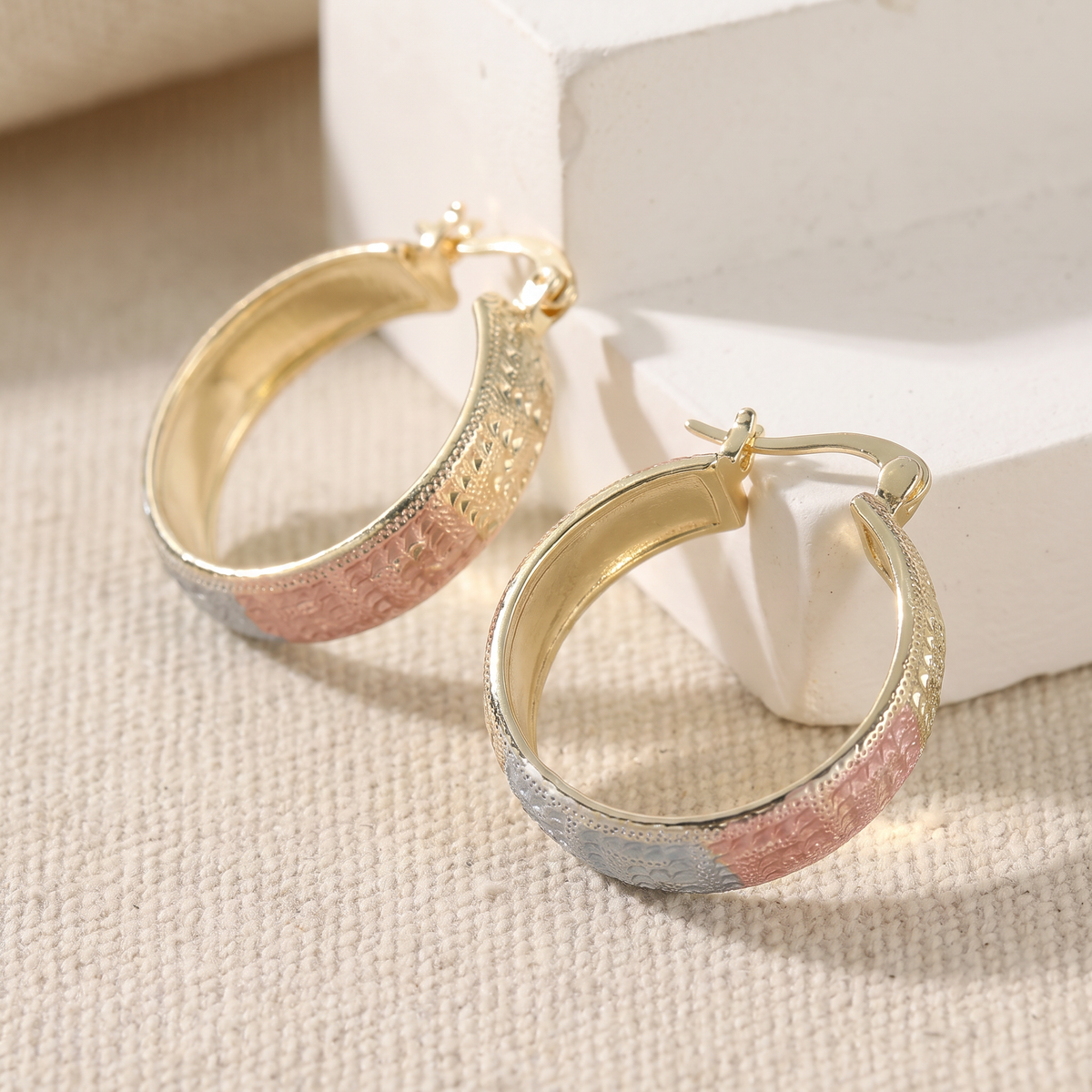 Tri-tone engraved wide hoop earrings on linen