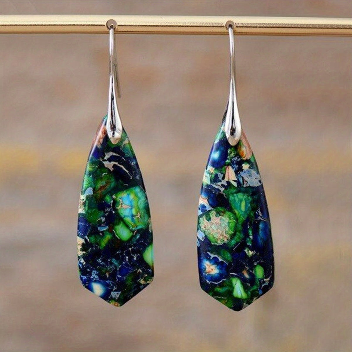 Long geometric earrings patterned in deep blue, bright green, and pale tones with silver-tone fittings.