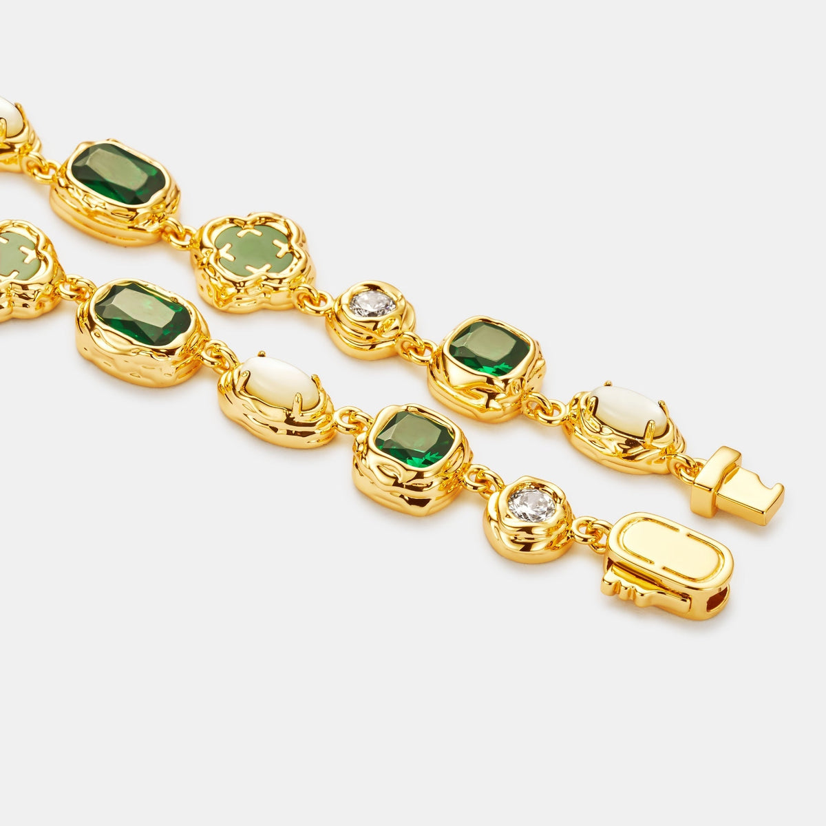 Close-up of gold-tone settings, green and pale accents, clear details, and clasp.