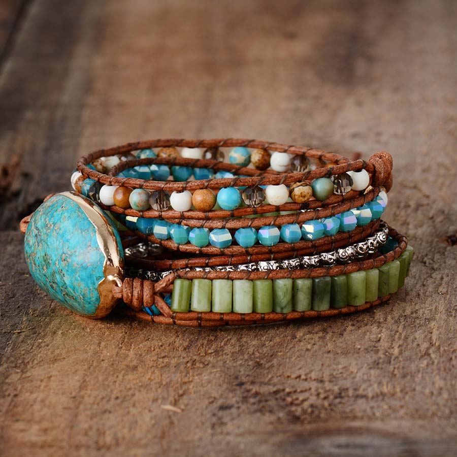 Side view of a turquoise-colored oval wrap bracelet with blue and green bead rows and brown cord.