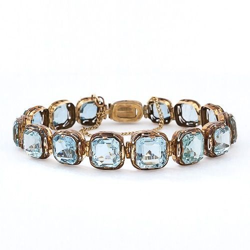 Bracelet of pale-blue faceted rectangular accents in textured gold-tone link settings.