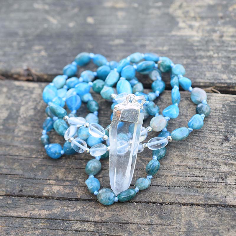 Long blue beaded necklace with clear oval accents and a clear pointed pendant in a silver-tone cap.
