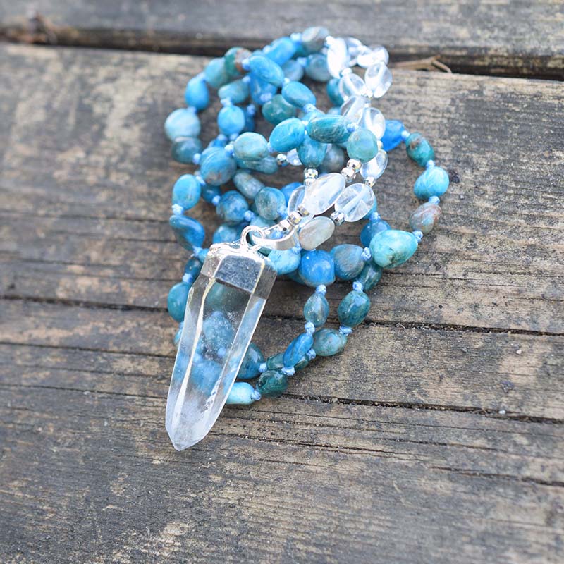Long blue beaded necklace with clear oval accents and a clear pointed pendant in a silver-tone cap.
