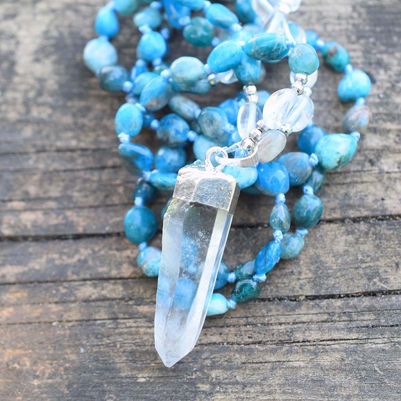 Long blue beaded necklace with clear oval accents and a clear pointed pendant in a silver-tone cap.