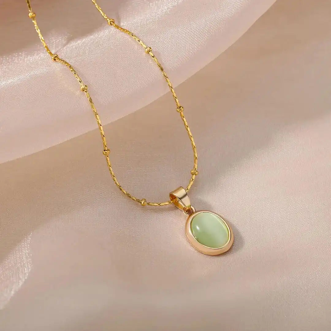 Pale-green oval pendant in a smooth gold-tone frame on a fine gold-tone chain.