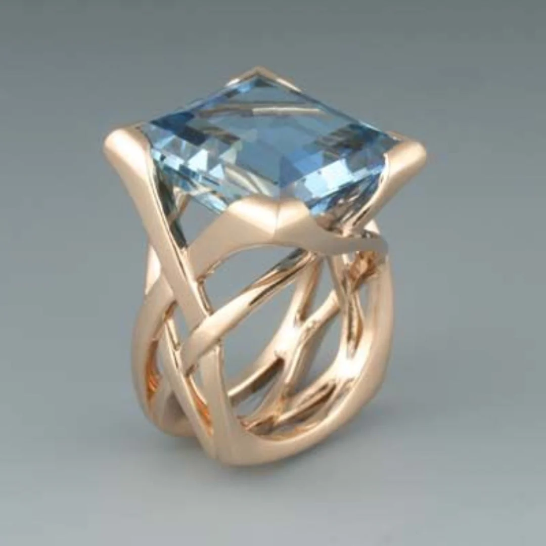 Ring with a large square faceted aqua-blue centerpiece and an open lattice band in a warm gold tone.