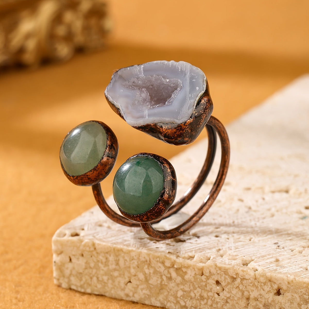 Copper-tone open ring with a pale geode-like center and two round green accents.