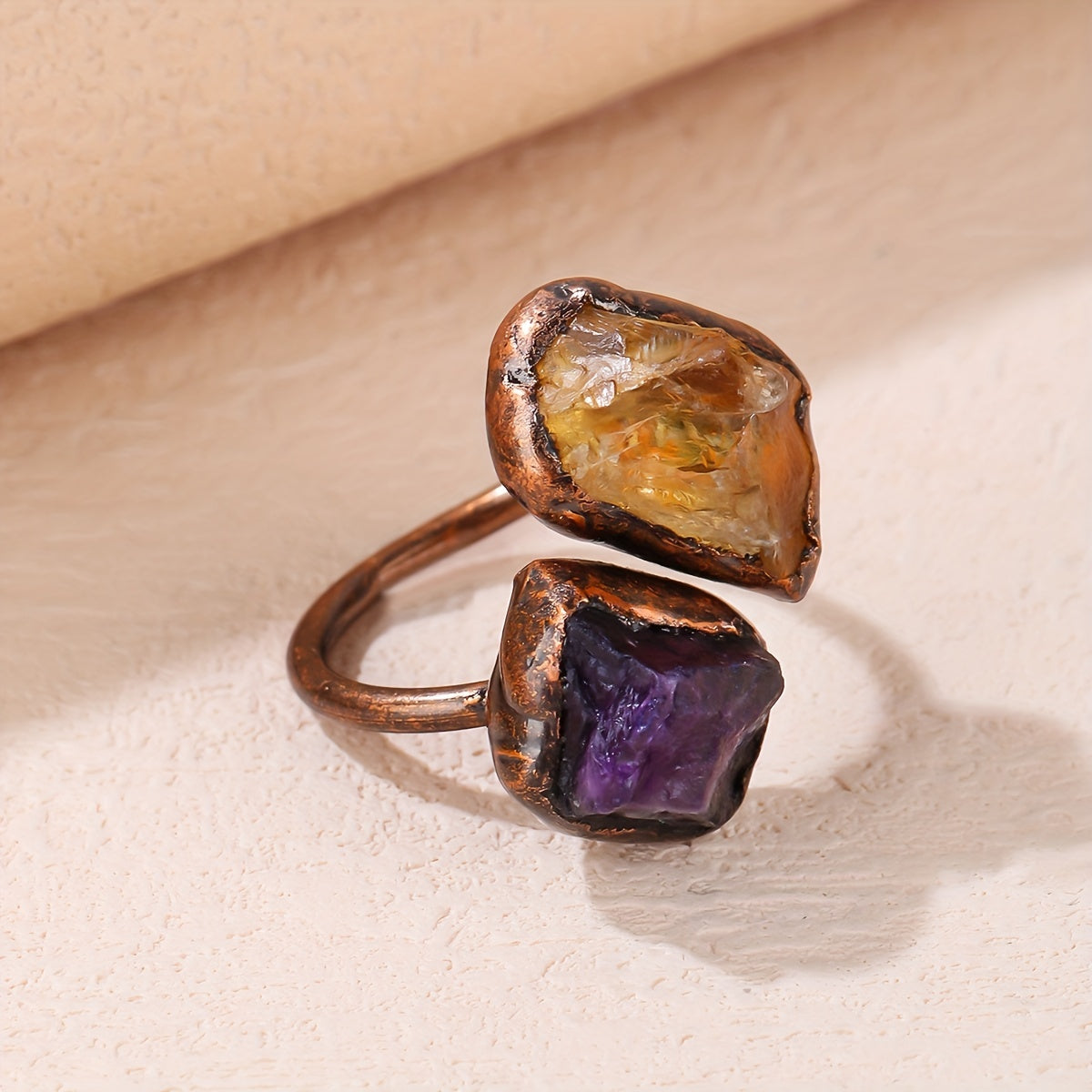 Copper-tone open ring with irregular amber-colored and purple accents in darkened frames.