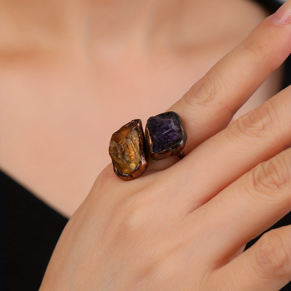 Copper-tone open ring with amber-colored and purple accents worn on a hand.
