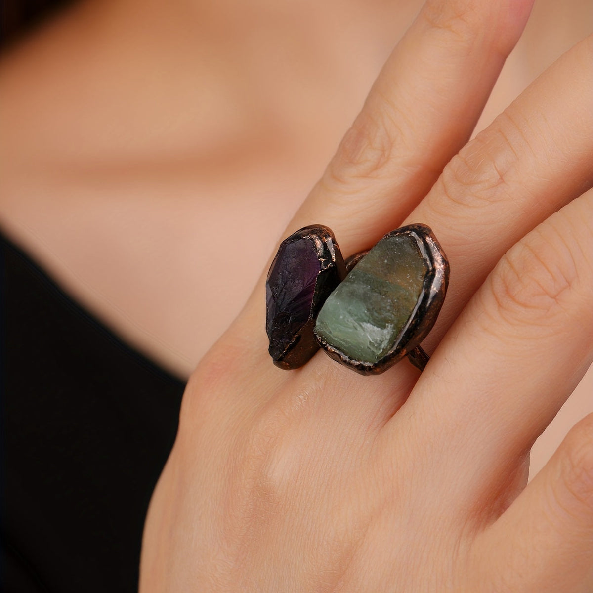 Copper-tone open ring with green and purple accents worn on a hand.