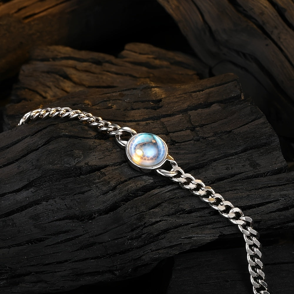 Silver-tone chain bracelet with a round pale iridescent center displayed on dark wood.