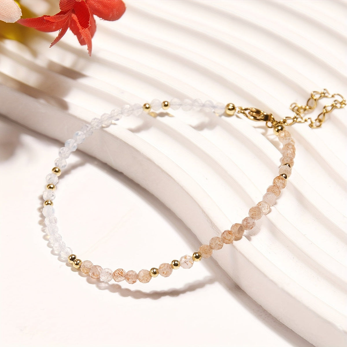 Fine bracelet with white and pale-peach faceted beads, gold-tone spacers, clasp, and extension chain.