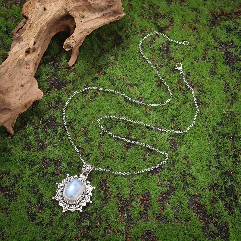 Pale blue-white oval pendant surrounded by an ornate silver-tone floral frame on a matching chain.