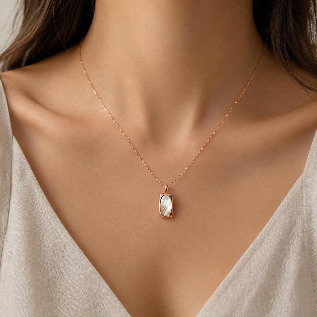 Model wearing a fine gold-tone beaded chain necklace with a small pale oval pendant.