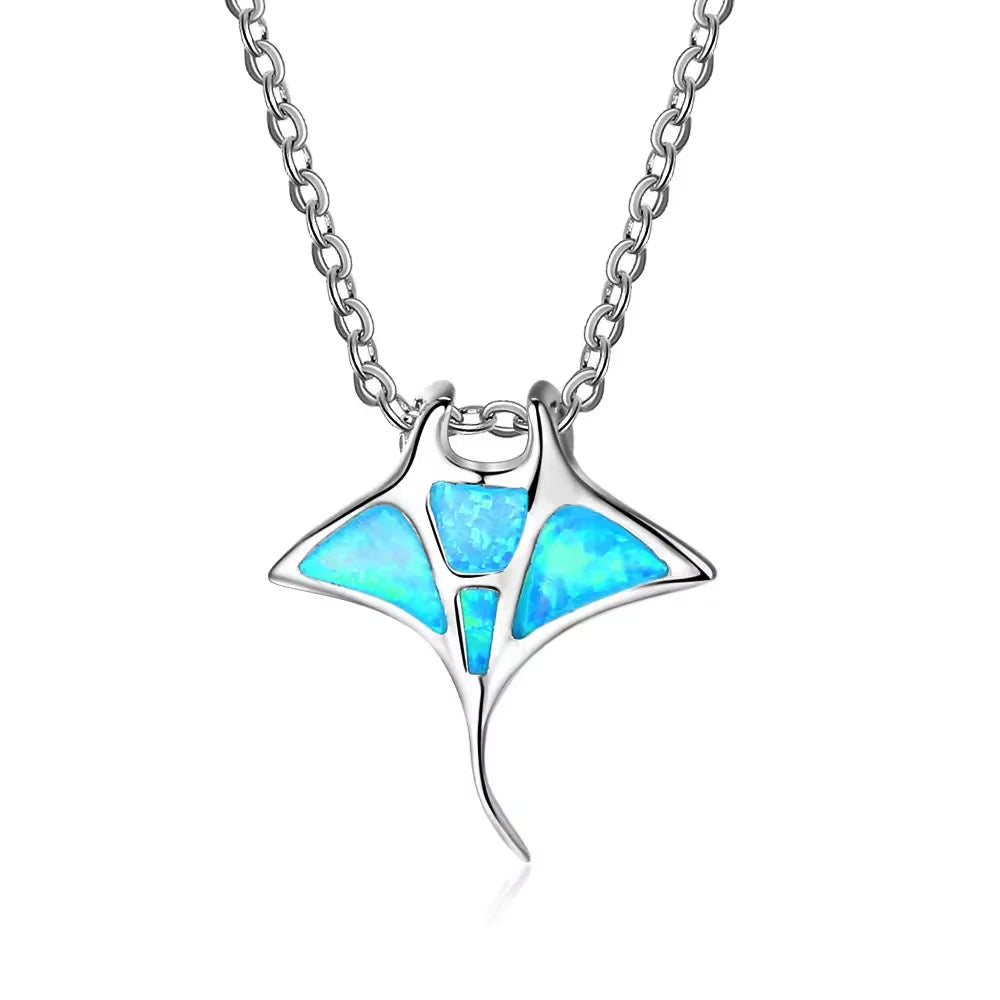 Silver-tone manta ray pendant with aqua iridescent-looking inlays and a curved tail on a chain.