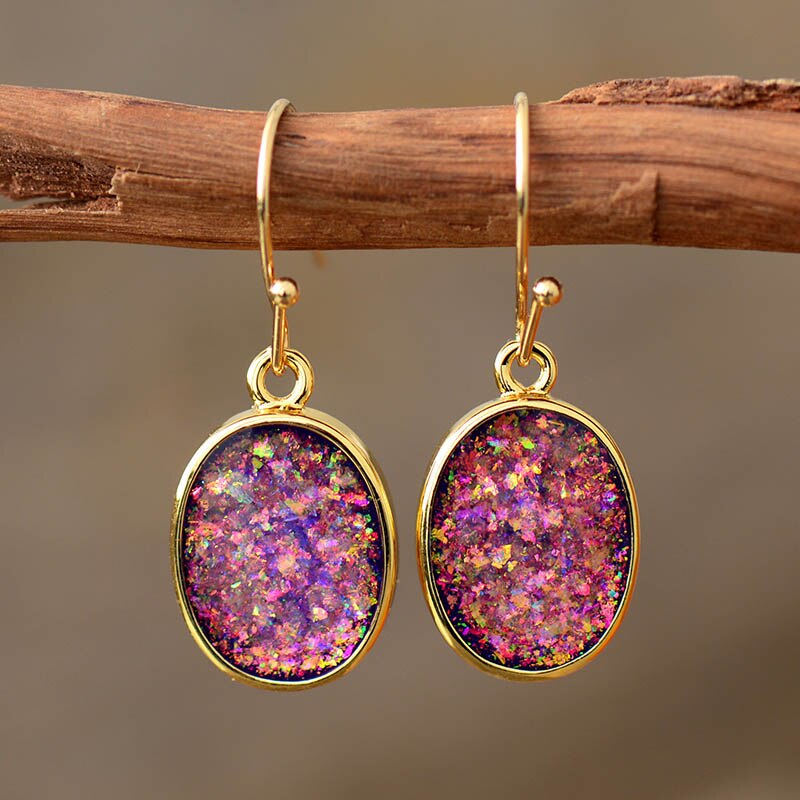 Pink iridescent-looking oval drop earrings with slim gold-tone borders and hooks.