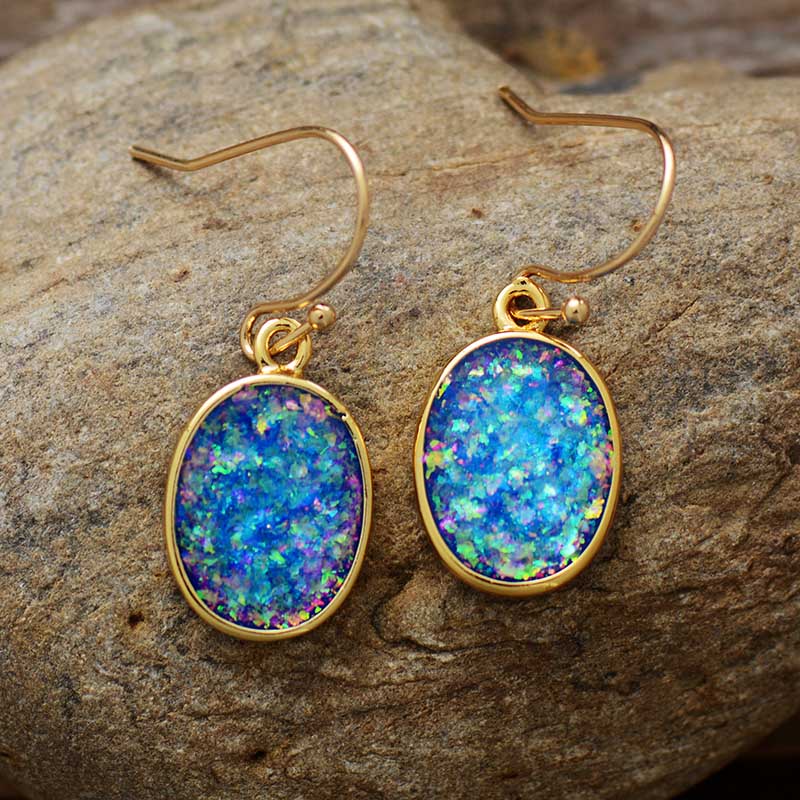 Blue-green iridescent-looking oval drop earrings with slim gold-tone borders and hooks.