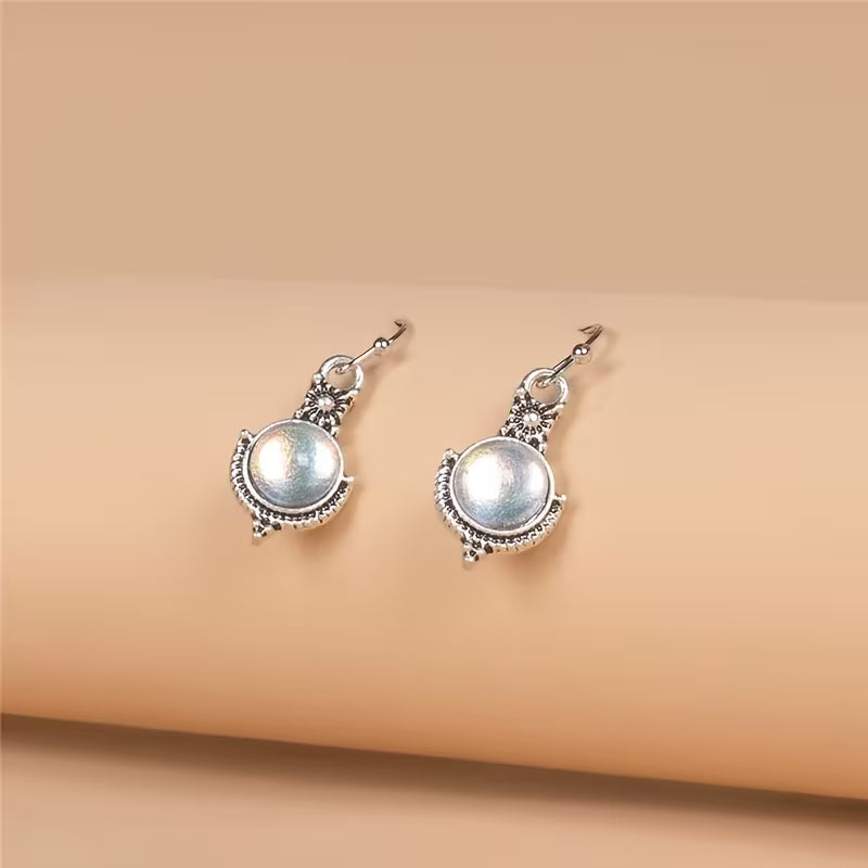 Round pale iridescent drop earrings with decorative silver-tone borders and hook fittings.
