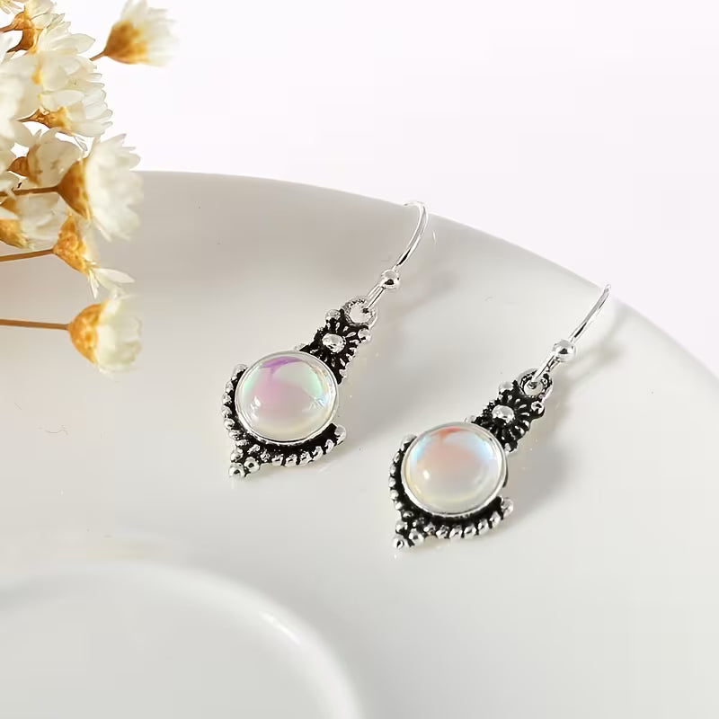 Round pale iridescent drop earrings with decorative silver-tone borders and hook fittings.