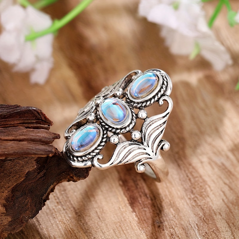 Wide silver-tone ring with three pale blue-white oval accents, rope-style borders, and open leaf-like sides.